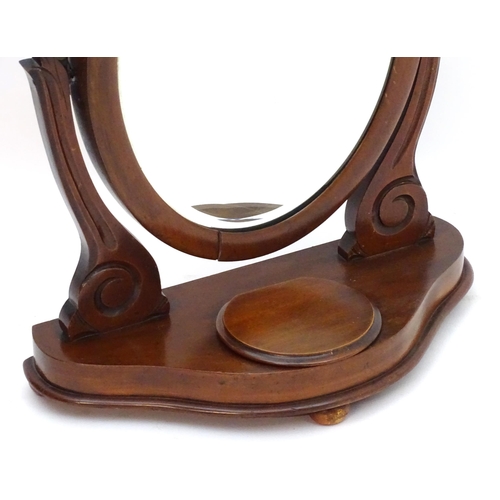 30 - A Victorian mahogany toilet mirror with an oval mirror and shaped surrounds above a moulded base wit... 
