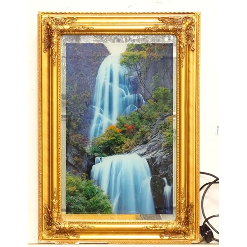57 - A backlit photograph of a waterfall with a mirrored background and a gilt frame. Approx. 26