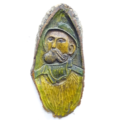 1406 - A carved wooden plaque depicting a portrait of a fisherman smoking a pipe. Ascribed in German verso.... 