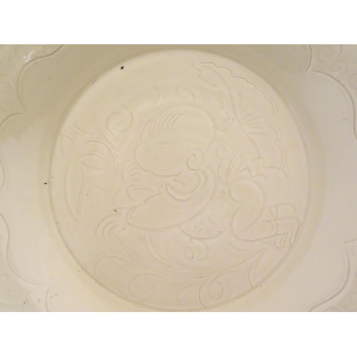 7 - A Chinese Ding style dished plate with relief decoration depicting a stylised baby. Approx. 8