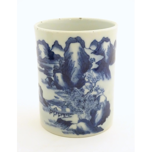 9 - A Chinese blue and white brush pot of cylindrical form decorated with a stylised landscape with moun... 