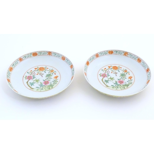 22 - A pair of Chinese plates / dishes with central roundels depicting flowers and a foliate border. The ... 
