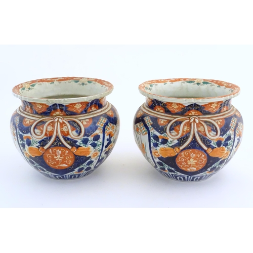 58 - A pair of Oriental planters / jardinieres decorated in the Imari with flowers, foliage and tassel bo... 