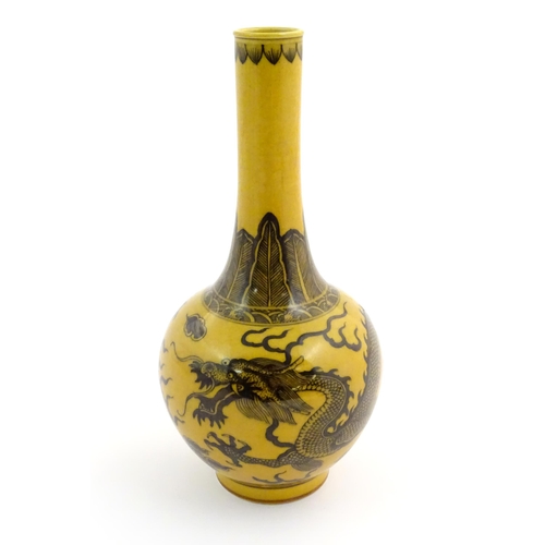 1 - A Chinese bottle vase with a yellow ground decorated with a dragon amongst stylised clouds. Characte... 