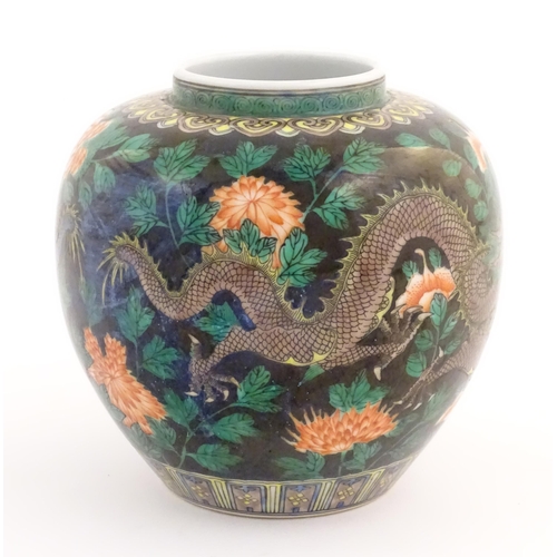 37 - A Chinese famille noir vase decorated with two dragons and a flaming pearl amongst flowers and folia... 