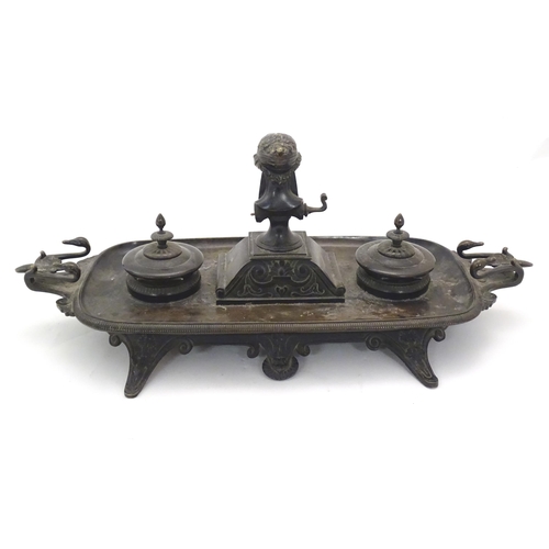1025 - A 19thC Continental bronze desk standish with twin handles modelled with swan heads, the central Cla... 