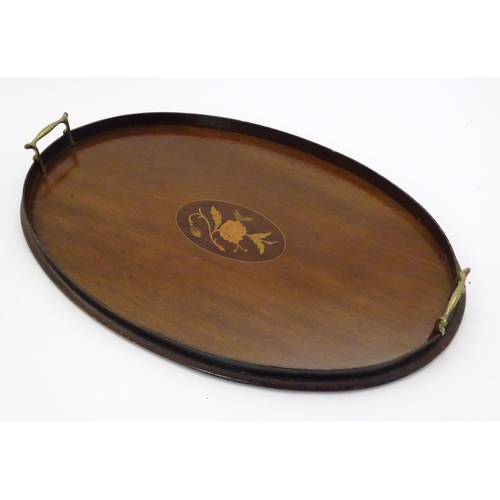 1027 - A late 19th / early 20thC mahogany tray of oval form with twin handles and central floral and foliat... 