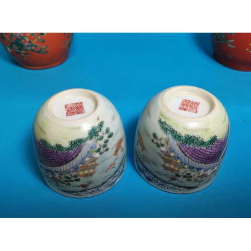281 - A pairof Chinese covered jars with reversable cup / covers decorated in polychrome against an orange... 