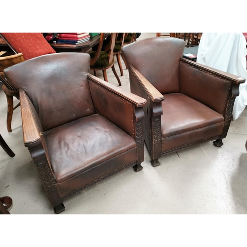 633 - A pair of 1920's oak armchairs, with low seats and leather effect studded upholstery