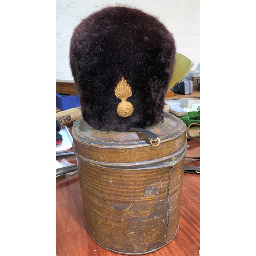 736 - A LANCASHIRE FUSILIERS bearskin hat with badge, plume and brass link chin strap, painted tin box