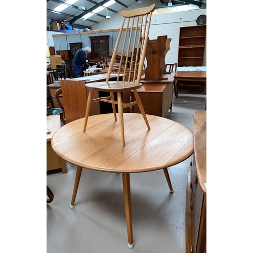 521 - An Ercol light oak dining suite comprising table with circular drop leaf top and 4 stick back chairs