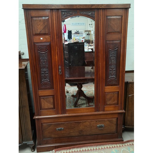 774A - An Edwardian walnut wardrobe with carved decoration, mirror door and base drawer.