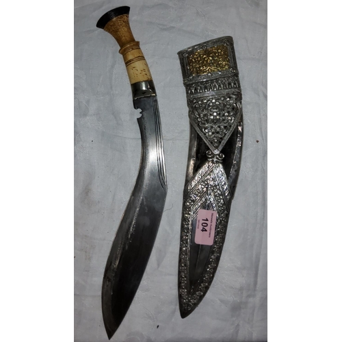 104 - A ceremonial bone handled kukri with ornate worked white metal and yellow metal scabbard, blade leng... 
