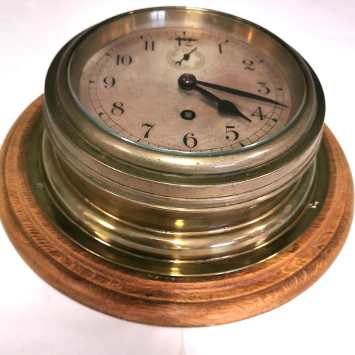 Antique brass ships clock on an oak mount 26cm diameter & Barnebys