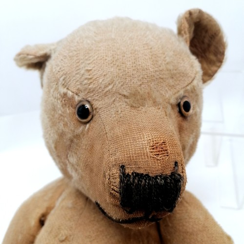 106 - Antique much loved teddy bear with glass eyes and cloth pads. straw filled. Some old repairs and los... 