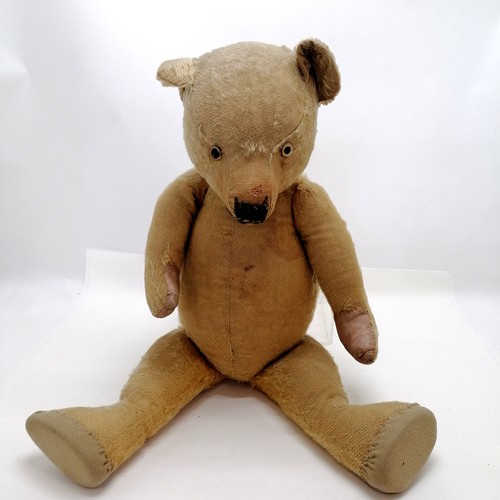 106 - Antique much loved teddy bear with glass eyes and cloth pads. straw filled. Some old repairs and los... 