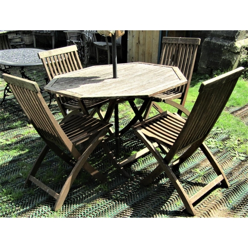 1550 - A weathered hardwood garden table, with hexagonal slatted top raised on folding X framed supports, t... 