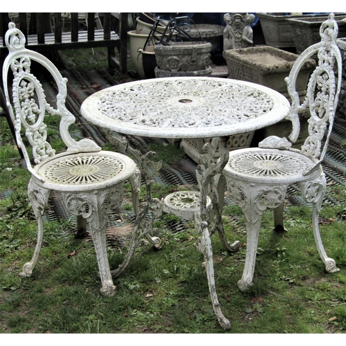 1504 - A weathered, painted cast aluminium garden terrace table, with circular pierced top raised on scroll... 