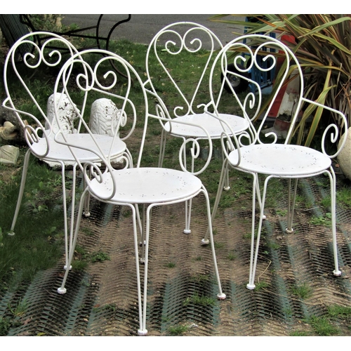 1546 - A set of four cream painted hoop back steel framed garden chairs, with pierced circular panelled sea... 