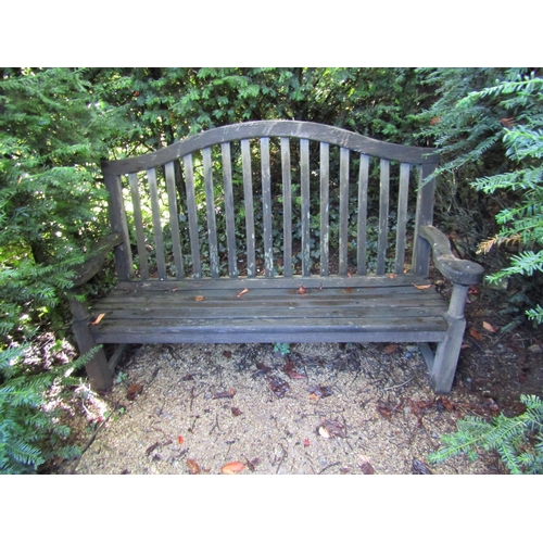 26 - A weathered teak wood garden bench, with scrolled arms and slatted back, 100cm wide