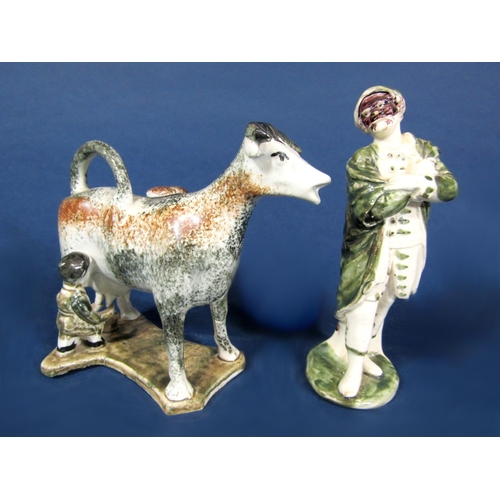 1061 - An early 19th century cow creamer in the Yorkshire manner with black and brown speckled glaze, raise... 