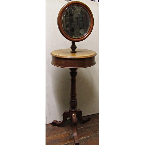A Victorian mahogany shaving stand, the circular mirror with bevelled edge plate, raised on adjustable brass column, the enclosed centre with rising lids, set on a turned pillar and tripod base