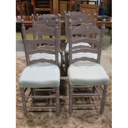 A harlequin set of twelve Lancashire style wavy ladderback dining chairs with rush seats, raised on turned supports and stretchers, all over later painted finish (slight variation in design), together with a further set of four ladderback examples with upholstered seats (16)