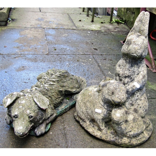 Three weathered cast composition stone garden ornaments in the form of a family of rabbits, a recumbent dog and a seated dragon