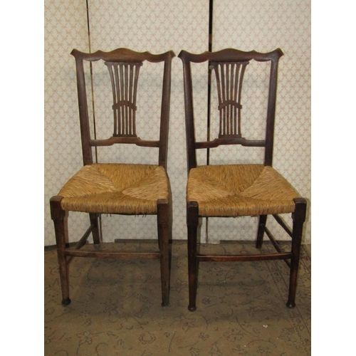 A set of six Edwardian cottage dining chairs with pierced splats and rush work seats