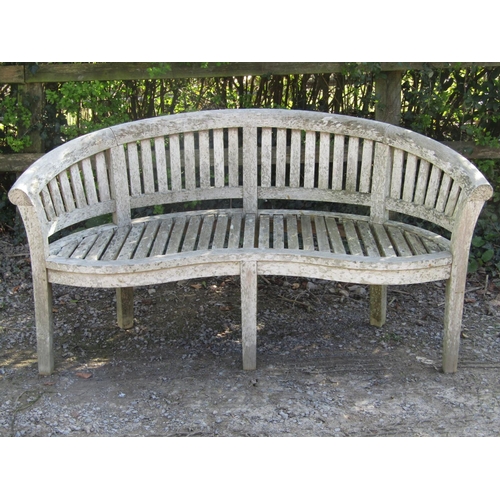 1 - A weathered teak banana shaped garden bench with slatted seat and back, 164cm long