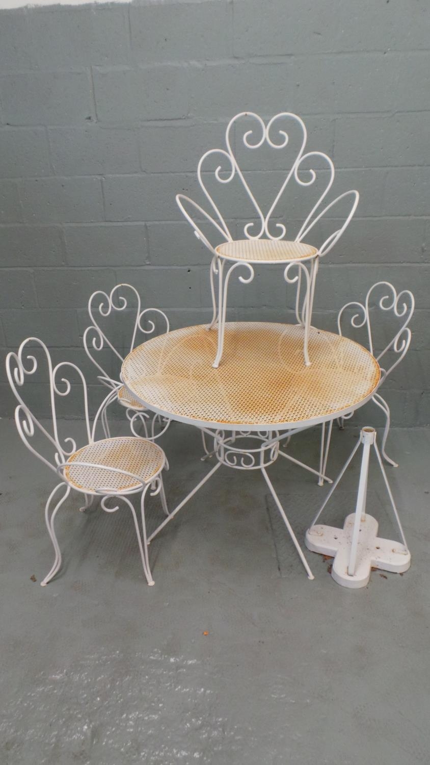 A metal garden table and four chairs with an added parasol base. Thne table measures approx' 99cm di