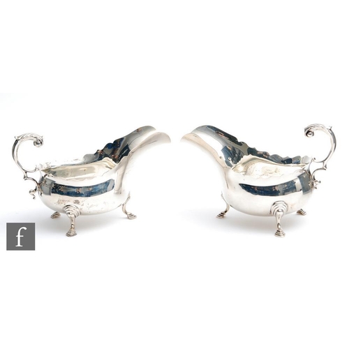 51 - A pair of hallmarked silver sauce boats each raised on three stepped pad feet below plain bodies, wa... 