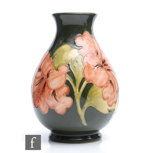 35 - A Moorcroft Pottery footed baluster vase decorated in the Hibiscus pattern with coral flowers agains... 