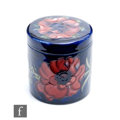 52 - A Moorcroft cylindrical box and cover decorated in the Anemone pattern with tubelined flowers agains... 