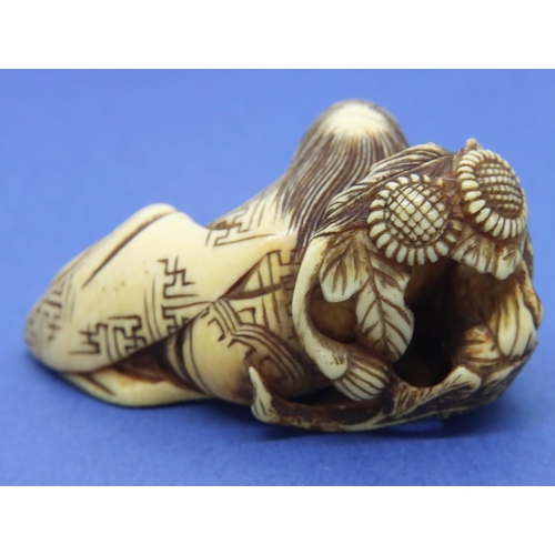 191 - Ivory carved netsuke in the form of a figure reclining with a floral background, L: 55 mm, unsigned.... 