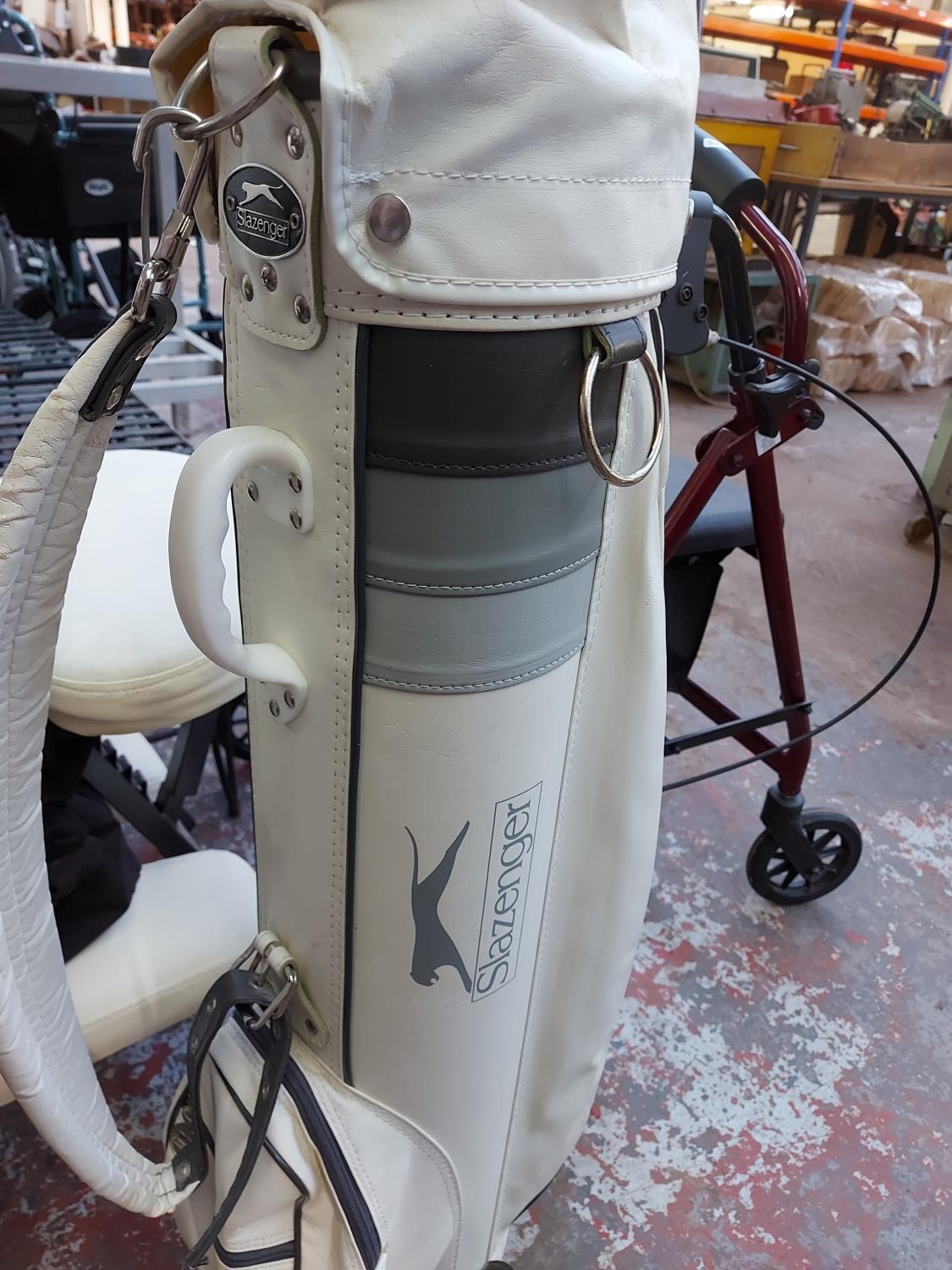 A white Slazenger golf bag containing Penfold golf clubs