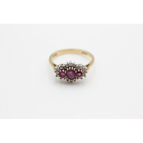 36 - A 9ct gold ruby and diamond three stone halo dress ring, size N½ - approx. gross weight 2.3 grams