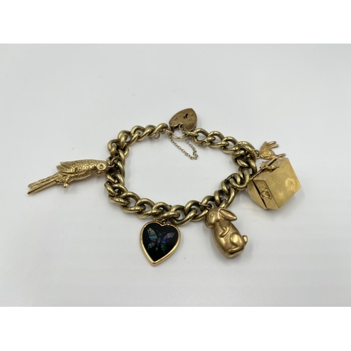 1141 - A 9ct gold charm bracelet with hallmarked Birmingham 9ct heart shaped clasp and five yellow metal ch... 