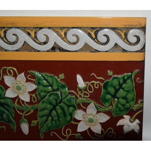 283 - Minton Hollins moulded majolica dado tile depicting white clematis on a burgundy ground with white &... 