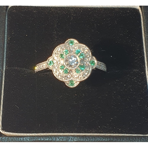 21 - An 18ct gold diamond and emerald dress ring. Total emerald weight 0.11ct. Total diamond weight 0.40c... 