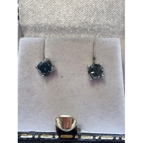 91 - A pair of White Gold and Blue Diamond Stud Earrings.