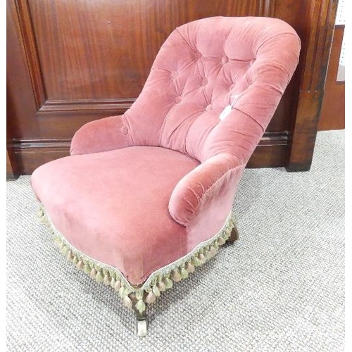 501 - A Victorian child's button-back armchair, upholstered in pink velour, on turned legs with brass caps... 