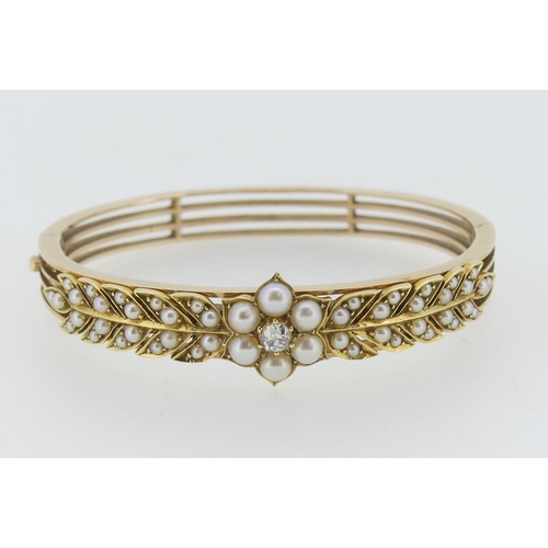 190 - An attractive Edwardian seed pearl and diamond Hinged Bangle, the front set with a central flowerhea... 