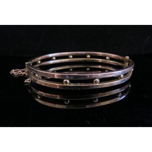 5002 - A gold bangle with open mid section joined by gold balls, stamped 9ct, saftey chain broken, 7g