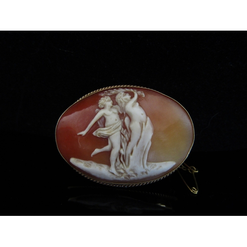 5051 - A carved cameo brooch depicting semi-clad male and female, stamped 9ct, 3.8cm x 4.8cm