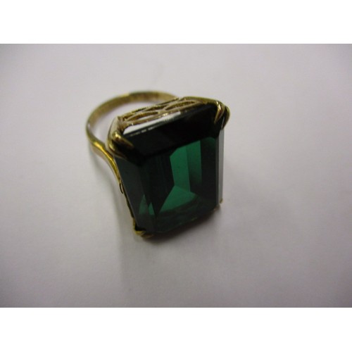 6 - A 9ct yellow gold ring set with a large green synthetic stone. Approximate weight 9.3g