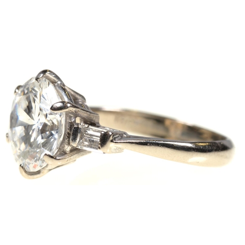 11 - A DIAMOND  RING   the round brilliant cut diamond of approx 3.2cts flanked by a baguette diamond to ... 