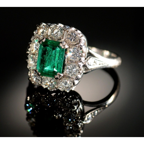 8 - AN EMERALD AND DIAMOND RING  the step cut emerald of approx 4 x 6mm in a surround of ten evenly size... 