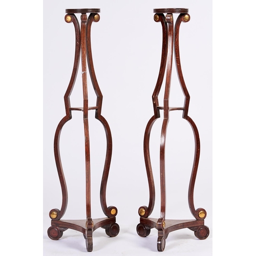 1434 - A pair of Regency brass mounted and brass line inlaid grained rosewood torcheres, of triple scrollin... 
