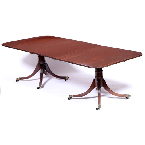 963 - A Regency style mahogany twin pillar dining table, the figured top with reeded lip above tapered cyl... 